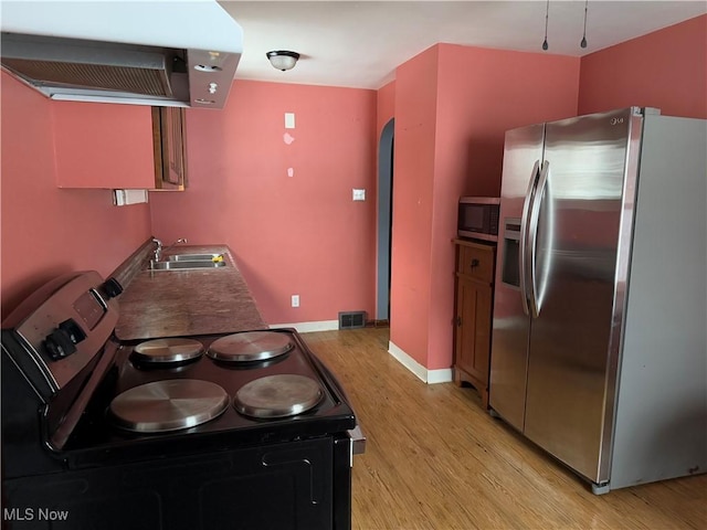 kitchen featuring exhaust hood, sink, stainless steel appliances, and light wood-type flooring