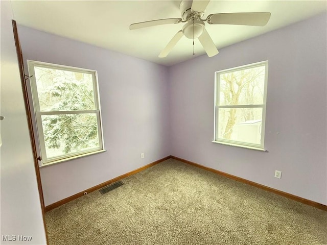 carpeted empty room featuring ceiling fan and a wealth of natural light