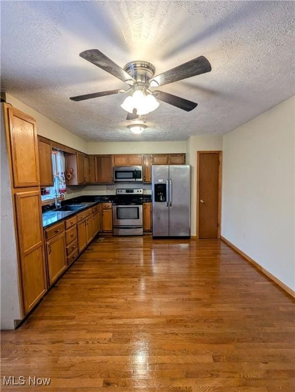 kitchen featuring appliances with stainless steel finishes, dark hardwood / wood-style flooring, a textured ceiling, ceiling fan, and sink