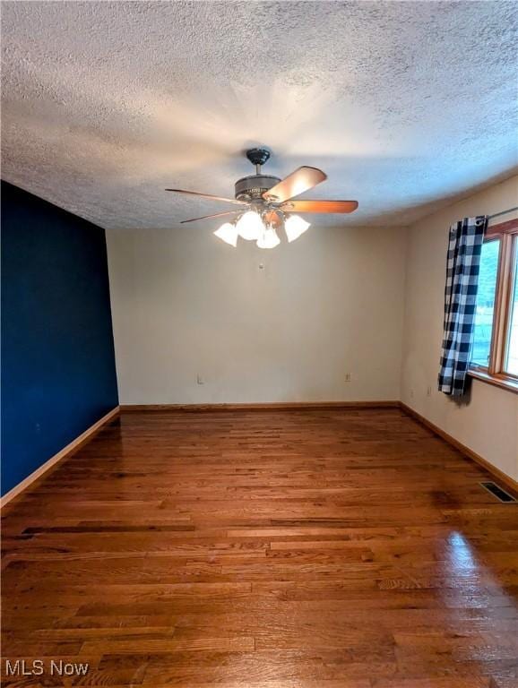 empty room with hardwood / wood-style floors, ceiling fan, and a textured ceiling