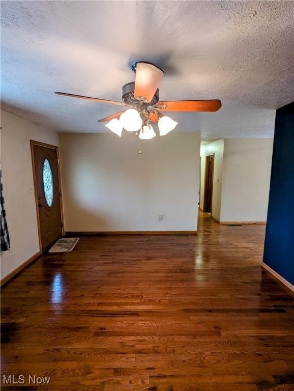 foyer entrance with a textured ceiling, ceiling fan, and dark wood-type flooring