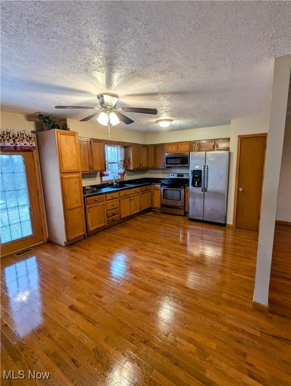 kitchen featuring hardwood / wood-style floors, sink, stainless steel appliances, and a textured ceiling