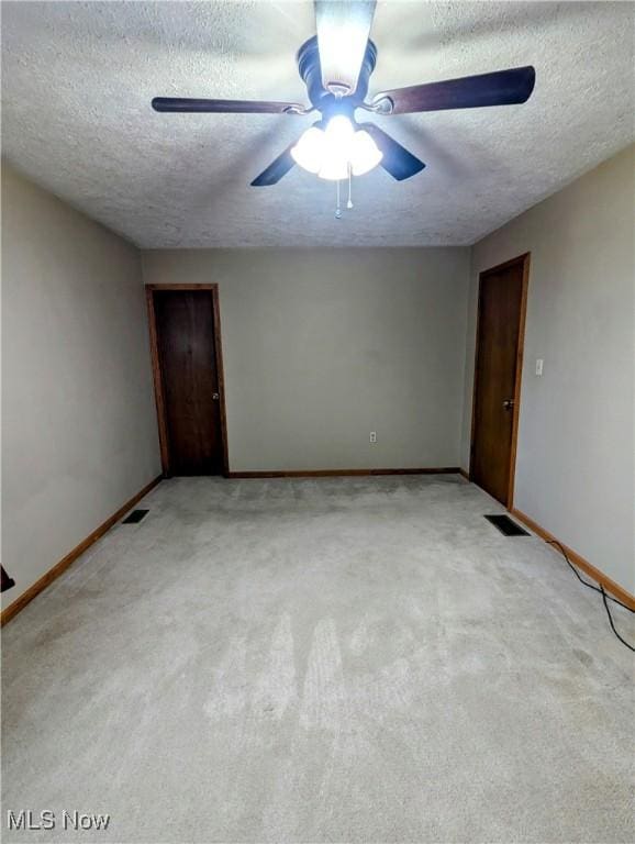 carpeted empty room with ceiling fan and a textured ceiling