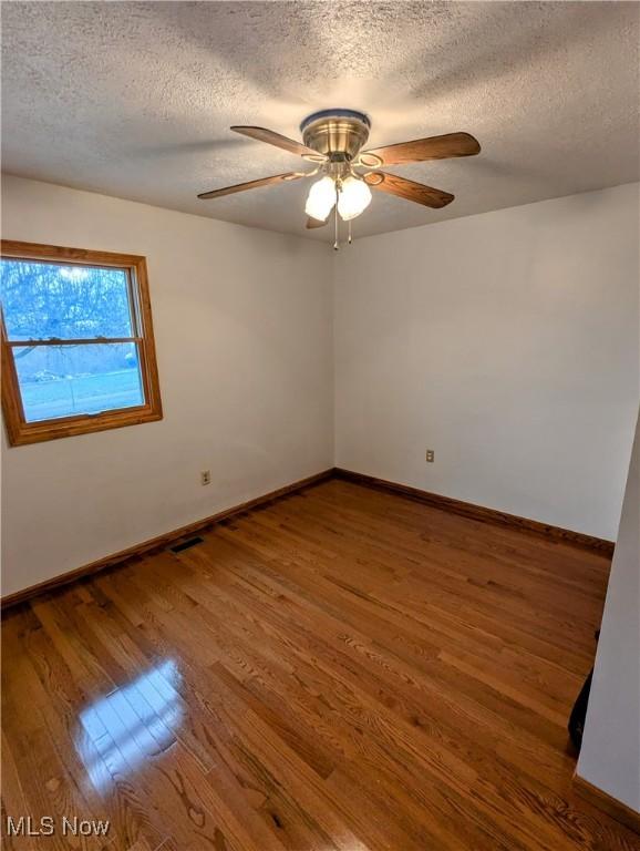 unfurnished room with a textured ceiling, hardwood / wood-style flooring, and ceiling fan