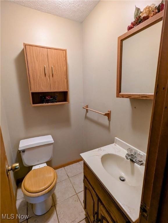 bathroom featuring tile patterned floors, vanity, a textured ceiling, and toilet