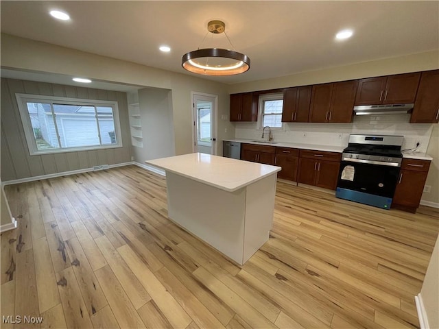 kitchen featuring sink, hanging light fixtures, stainless steel appliances, light hardwood / wood-style floors, and a kitchen island