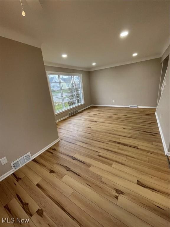 spare room with crown molding and light hardwood / wood-style flooring