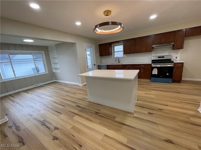 kitchen with pendant lighting, sink, light hardwood / wood-style floors, and stainless steel range with gas stovetop