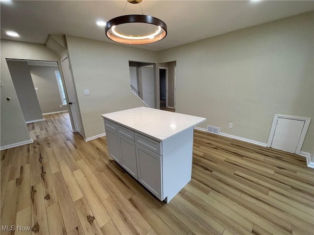 kitchen featuring decorative light fixtures, a center island, and light hardwood / wood-style floors