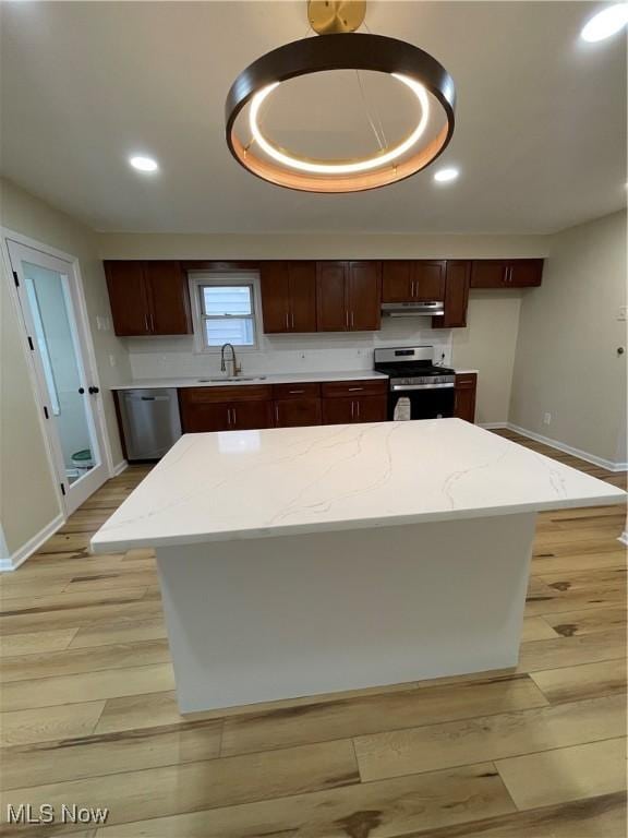 kitchen featuring light wood-type flooring, appliances with stainless steel finishes, a center island, and sink