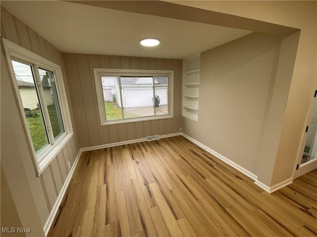 empty room featuring built in features and light wood-type flooring