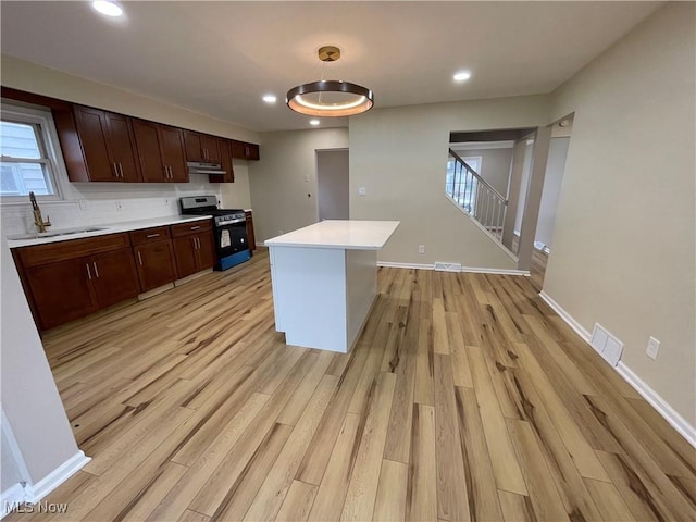 kitchen with a center island, stainless steel gas range oven, light hardwood / wood-style floors, and sink