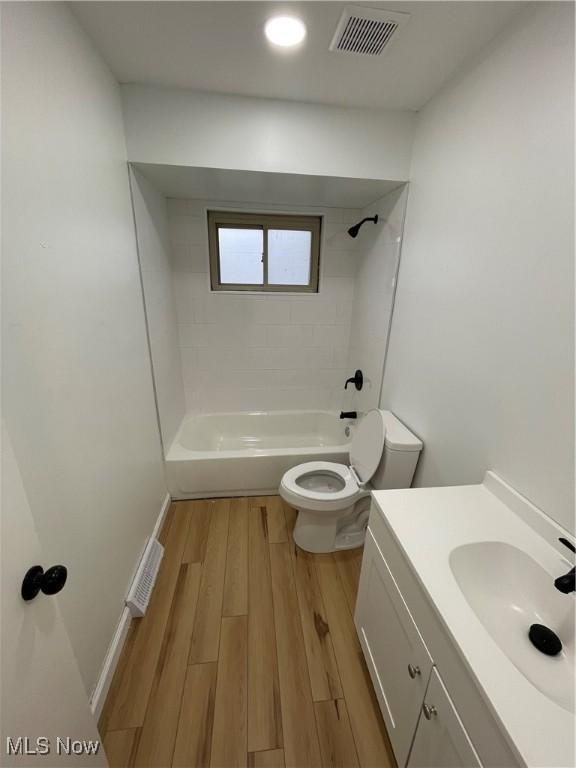 full bathroom featuring vanity, toilet, wood-type flooring, and tiled shower / bath