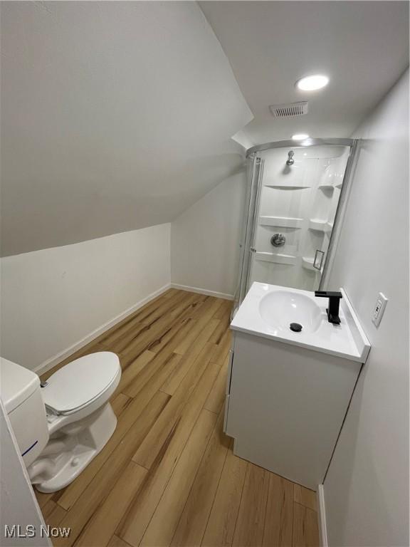 bathroom featuring hardwood / wood-style floors, vanity, a shower with shower door, and lofted ceiling