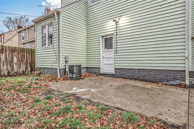 view of exterior entry with a patio and central AC unit