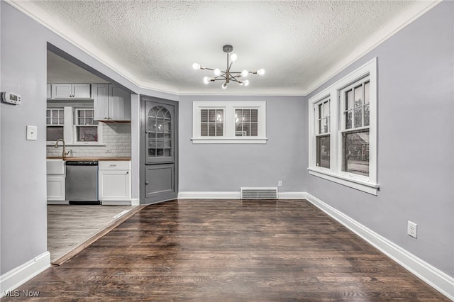 kitchen with a textured ceiling, dark hardwood / wood-style floors, stainless steel dishwasher, and an inviting chandelier