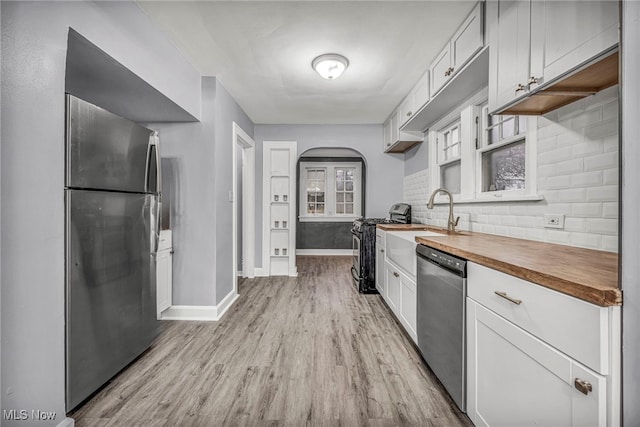 kitchen featuring white cabinets, sink, light hardwood / wood-style flooring, butcher block counters, and stainless steel appliances