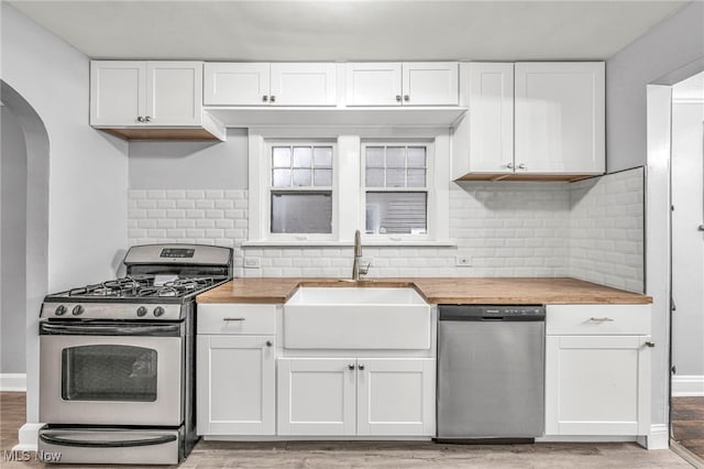 kitchen with wood counters, white cabinetry, sink, and appliances with stainless steel finishes