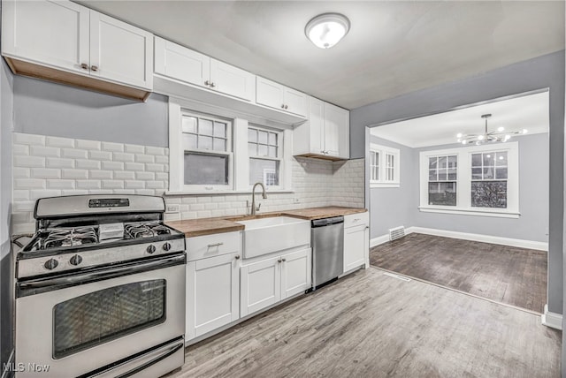 kitchen featuring wooden counters, stainless steel appliances, and white cabinets