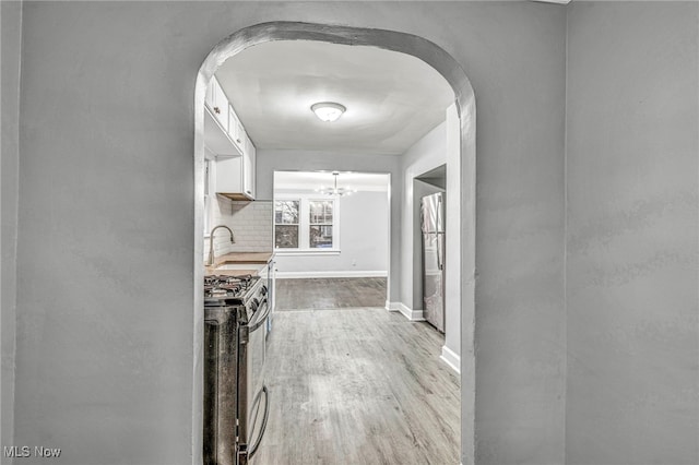 hallway with a chandelier, light hardwood / wood-style flooring, and sink