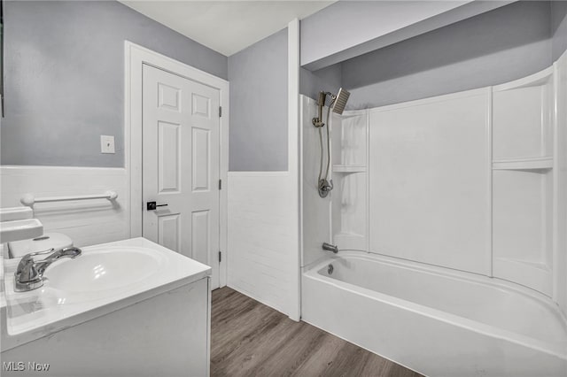 bathroom with vanity, hardwood / wood-style floors,  shower combination, and tile walls