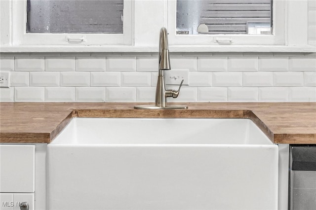 details with backsplash, white cabinetry, and sink