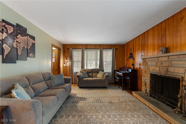 living room featuring a stone fireplace and wooden walls