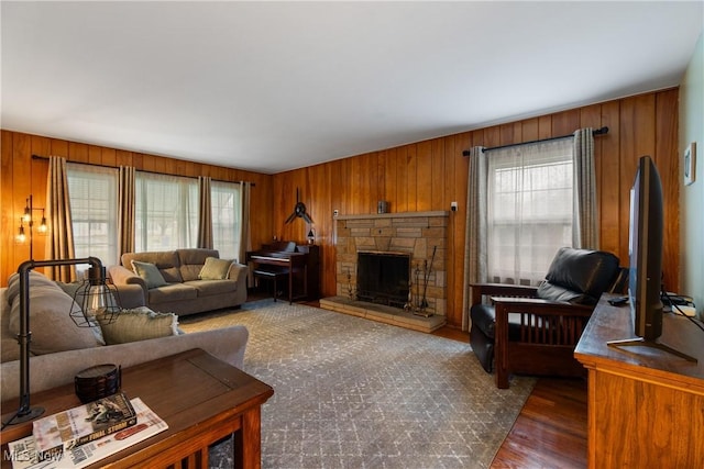 living room with a fireplace, wood walls, dark wood-type flooring, and a healthy amount of sunlight