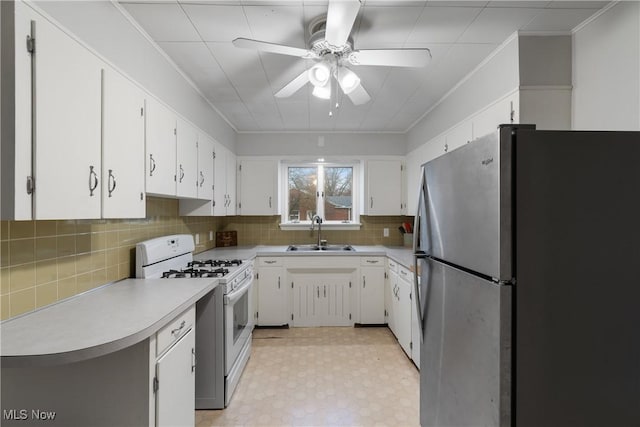 kitchen with white cabinets, sink, ceiling fan, stainless steel refrigerator, and white range with gas cooktop