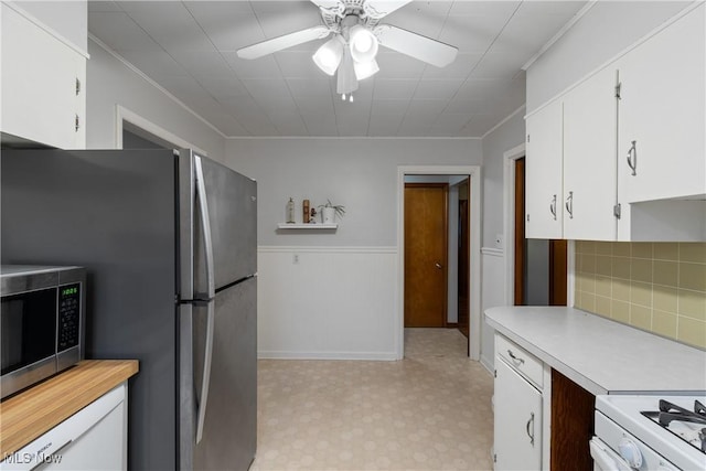 kitchen with white cabinets, ceiling fan, ornamental molding, appliances with stainless steel finishes, and tasteful backsplash