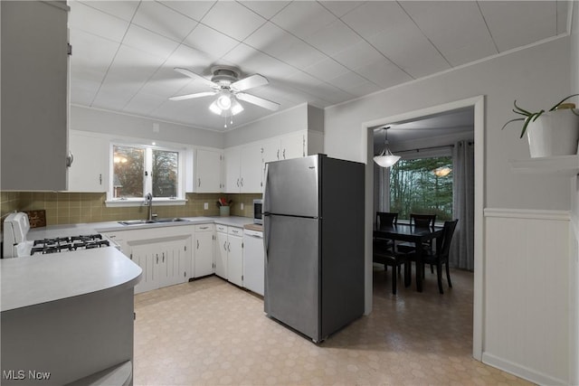 kitchen with range, white cabinetry, stainless steel refrigerator, and a healthy amount of sunlight