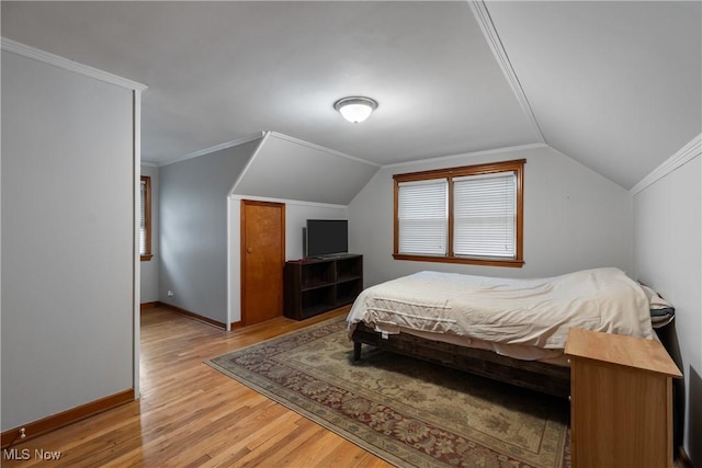 bedroom with light hardwood / wood-style floors, vaulted ceiling, and crown molding