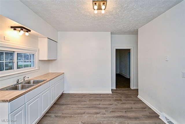 kitchen with white cabinets, wooden counters, light hardwood / wood-style flooring, and sink