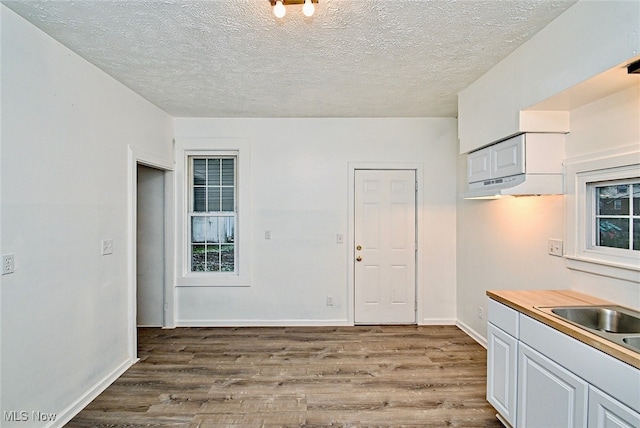 kitchen with white cabinets, light hardwood / wood-style floors, sink, and a textured ceiling