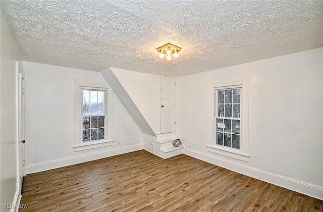 bonus room featuring a textured ceiling and dark wood-type flooring