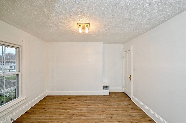 unfurnished room with a textured ceiling and hardwood / wood-style flooring