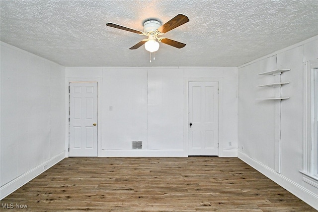 empty room with a textured ceiling, dark hardwood / wood-style floors, and ceiling fan