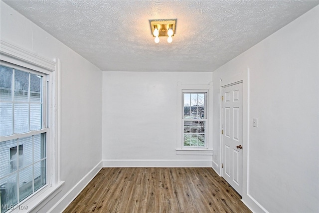 empty room with a textured ceiling and dark hardwood / wood-style flooring