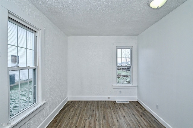 empty room with dark hardwood / wood-style floors and a textured ceiling