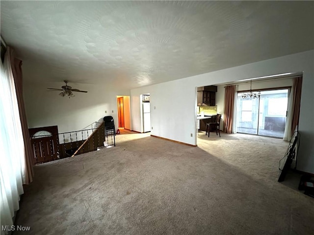 unfurnished living room with carpet and ceiling fan with notable chandelier