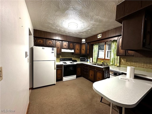 kitchen featuring dark brown cabinetry, sink, tasteful backsplash, kitchen peninsula, and white appliances