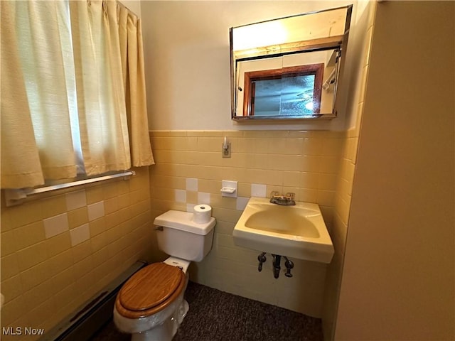 bathroom featuring toilet, tile walls, and sink