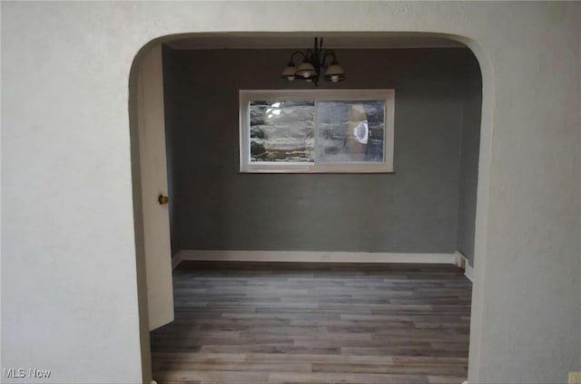 unfurnished dining area featuring dark hardwood / wood-style flooring and an inviting chandelier