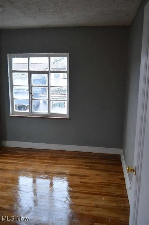 unfurnished room with hardwood / wood-style floors and a textured ceiling