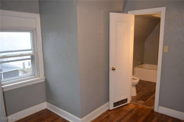 bathroom with a washtub, hardwood / wood-style floors, and toilet