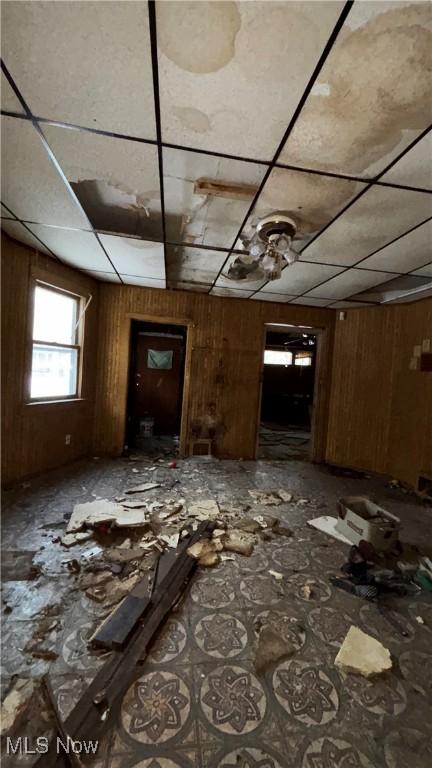 miscellaneous room featuring a paneled ceiling and wooden walls