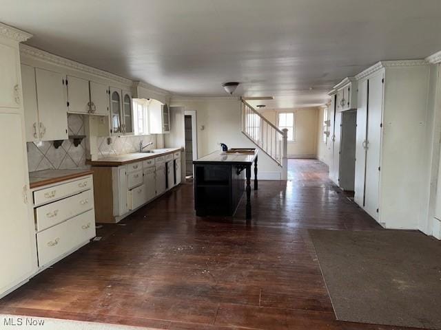 kitchen with ornamental molding, a center island, dark hardwood / wood-style flooring, and decorative backsplash