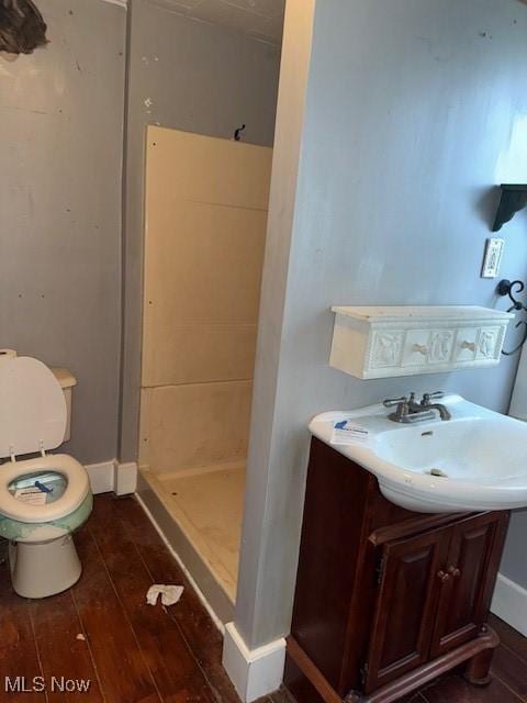 bathroom with sink, hardwood / wood-style floors, toilet, and walk in shower