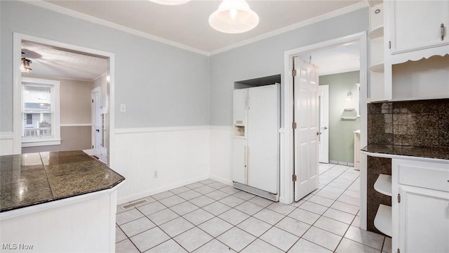 kitchen featuring tasteful backsplash, ornamental molding, white refrigerator with ice dispenser, white cabinets, and light tile patterned flooring