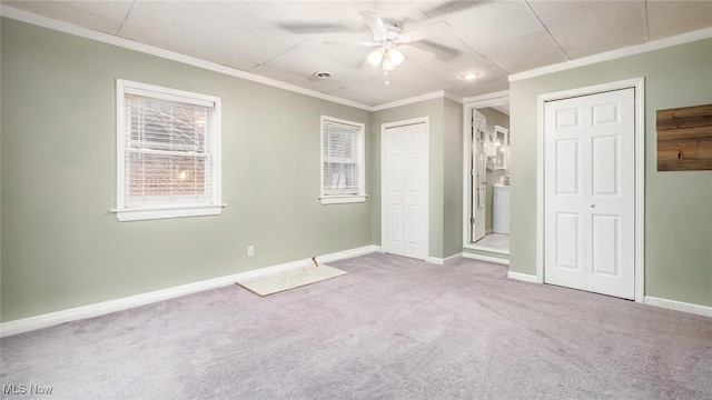 unfurnished bedroom with light carpet, multiple closets, ceiling fan, and crown molding